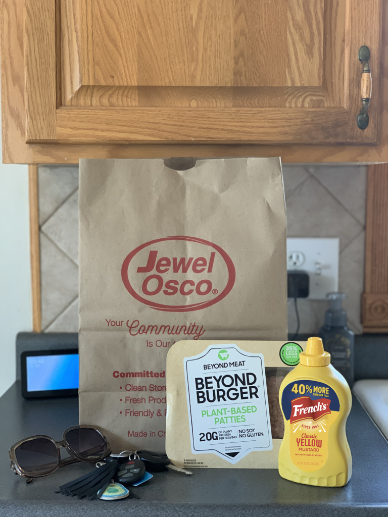 Kitchen lifestyle photo with Jewel-Osco bag pictured with Beyond Burger plant based patties, a bottle of French's yellow mustard